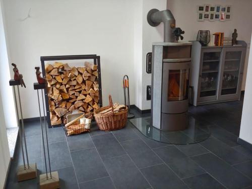 a room with a fireplace and a pile of wood at Ruhiges Ferienhaus mit viel Platz und Ladestation für E-Auto in Masserberg