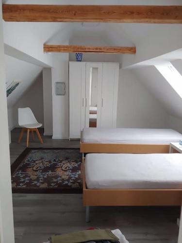 a attic room with two beds and a chair at Ruhiges Ferienhaus mit viel Platz und Ladestation für E-Auto in Masserberg