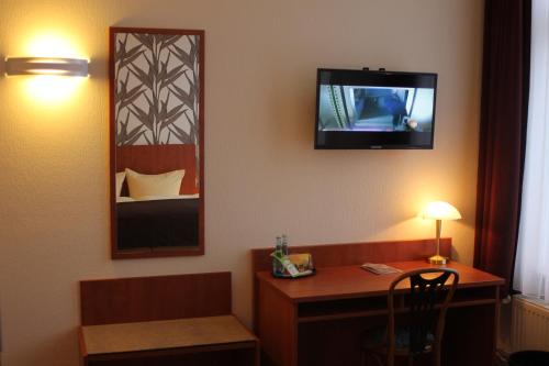 a hotel room with a desk and a tv on the wall at Hotel Schwarzer Adler Jever in Jever