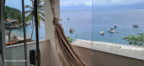 a balcony with a view of the water and boats at Suítes Encanto do Pai in Praia de Araçatiba