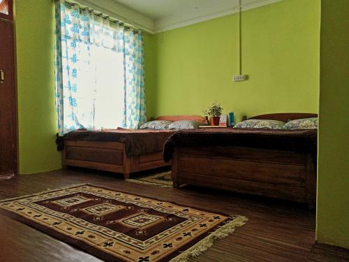 two beds in a green room with a rug at Ratna Homestay & Restaurant in Darjeeling