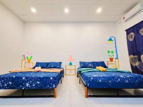 two beds in a room with blue sheets at GOLDEN HOUSE ,1min to aeon, 7min to zoo,8min to lake gardens in Taiping
