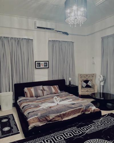 Un dormitorio con una cama grande y una lámpara de araña. en Yawang homestay, en Kota Bharu