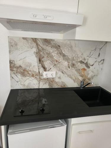 een aanrecht met een spoelbak en een marmeren muur bij Studio 1 in Luxemburg