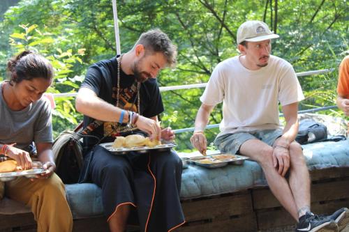 a group of people sitting on a wall eating food at Kyarki Village Homestay & Cafe in Rishīkesh