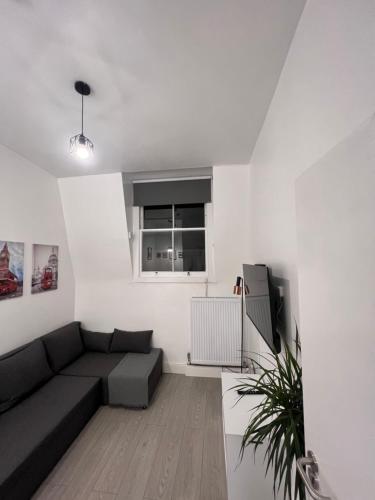 a living room with a black couch and a window at 2 Bed Apartment in Central London on 3rd floor - Newly refurbished - No lift in London