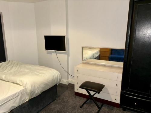 a bedroom with a bed and a tv and a chair at Stainless Guests house in Dudley
