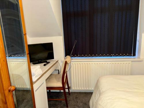 a bedroom with a bed and a desk with a television at Stainless Guests house in Dudley