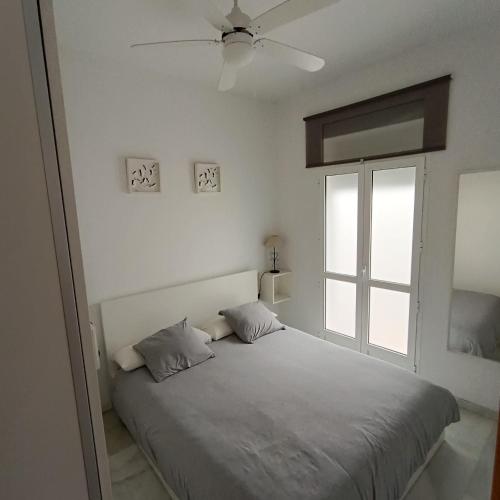 a white bedroom with a bed and a window at El Rincón de Don Gonzalo in Puente Genil