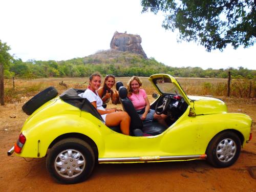 three people sitting in a yellow car on a dirt road at The Nilmini Lodge in Sigiriya