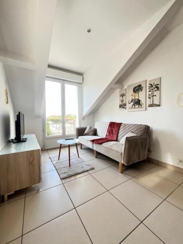 un salon avec un canapé et une télévision dans l'établissement Duplex-Trois pas de la Gare, à Sartrouville