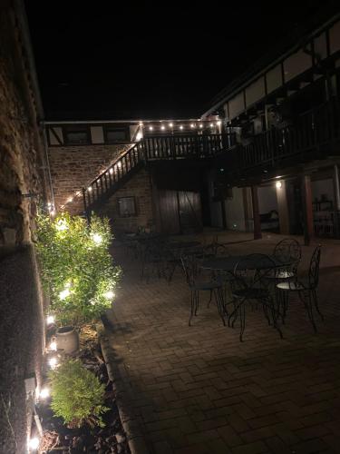 an outdoor patio with tables and lights at night at Relais du Dompeter in Molsheim