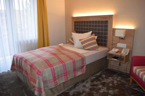 a bedroom with a bed with a phone on a table at Eden Hotel in Bad Krozingen
