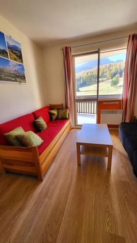 un salon avec un canapé rouge et une table dans l'établissement Appartement d'angle , les Issarts, à Superdevoluy