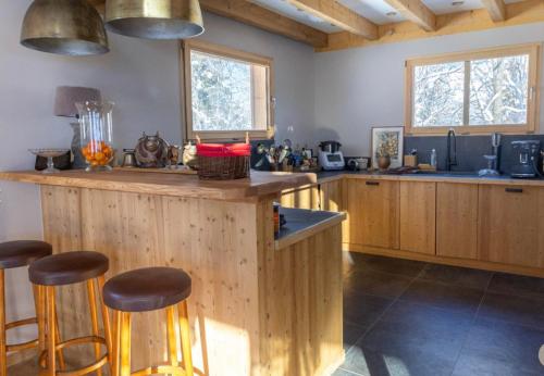 une cuisine avec des armoires en bois et un comptoir avec des tabourets dans l'établissement Chalet prestige Saint Gervais les Bains, à Saint-Gervais-les-Bains