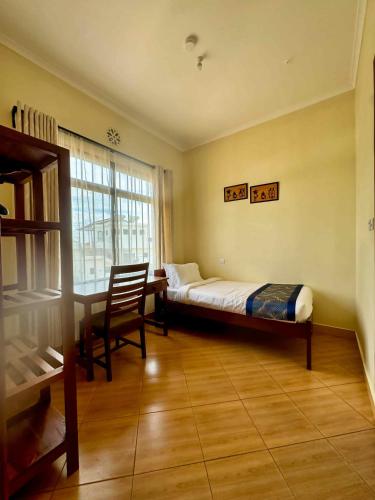 a bedroom with a bed and a desk and a window at Moshono Hillside in Arusha