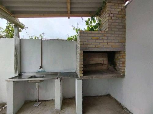 a kitchen with a brick fireplace and a table at Casa Barra do Chuí Brasil in Santa Vitória do Palmar