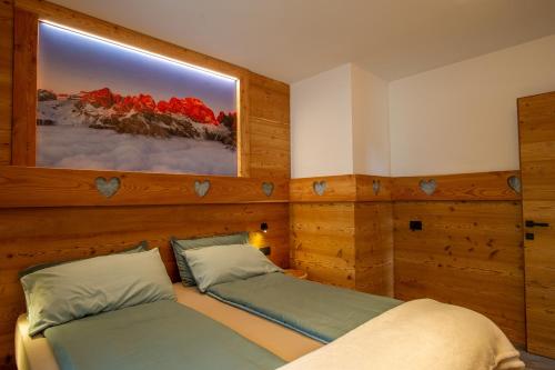 a bedroom with two beds and a picture on the wall at Dolomites Chalet Wolf 2 in Molveno