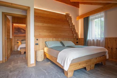 a bedroom with a bed in a room with wooden walls at Dolomites Chalet Wolf 2 in Molveno