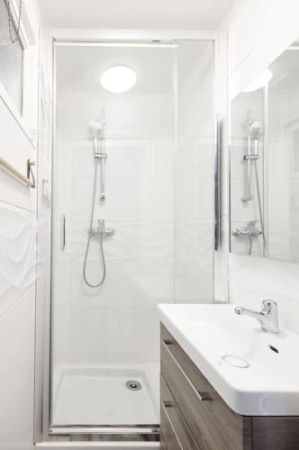 une salle de bain blanche avec une douche et un lavabo dans l'établissement Les Halles by Paul Riquet 1609, à Béziers