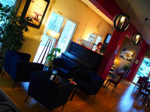 a living room with a piano and chairs at The Originals City, Hôtel et Restaurant Aster, Saint-Avold Nord in Creutzwald-la-Croix