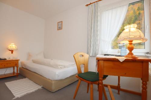 a bedroom with a bed and a desk with a lamp at Landgasthaus Kurz Hotel & Restaurant am Feldberg - Schwarzwald in Todtnau