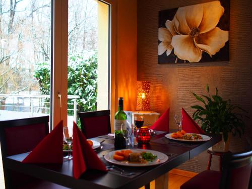 a table with two plates of food and a bottle of wine at The Originals City, Hôtel et Restaurant Aster, Saint-Avold Nord in Creutzwald-la-Croix