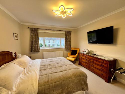 a bedroom with a bed and a television and a chair at Hotel at Home in Shoreham by Sea in Shoreham-by-Sea