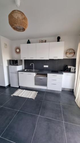 une cuisine avec des armoires blanches et un sol carrelé dans l'établissement Le cocon effet'mer, à La Teste-de-Buch