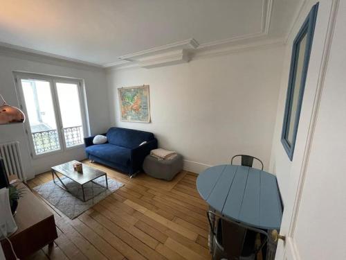 un salon avec un canapé bleu et une table dans l'établissement Charming and bright flat in a very convenient area, à Paris