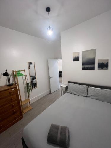 a bedroom with a bed and a dresser and pictures on the wall at 2 Bed Apartment in Central London on 3rd floor - Newly refurbished - No lift in London
