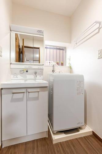 a white bathroom with a sink and a mirror at kensui house in Tokyo