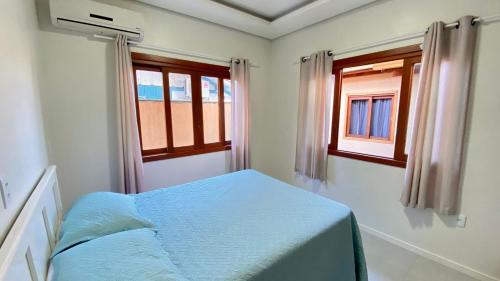a bedroom with a bed and two windows at Casa praia bombinhas 130m mar in Bombinhas