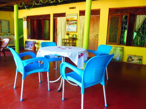 a table and chairs with a white table and blue chairs at The Nilmini Lodge in Sigiriya
