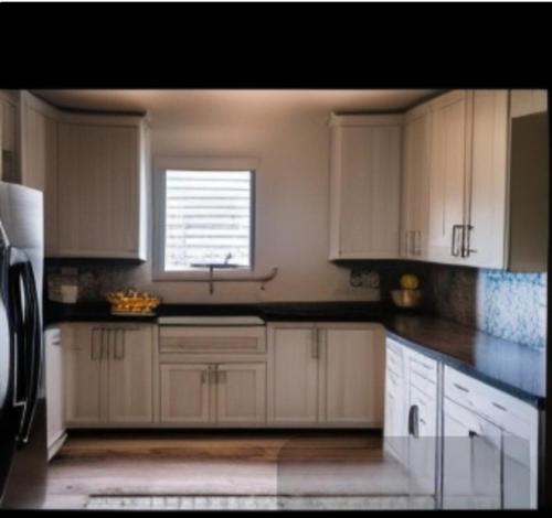a kitchen with white cabinets and a window at Three bedroom house for stay in seeta town mukono in Seeta