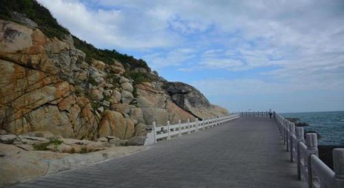 a boardwalk leading to the ocean next to a cliff at Beluga Sanya Discovery Ocean World in Shangsimacun
