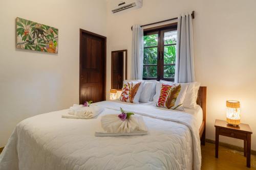 a bedroom with a large bed with white sheets and pillows at Pousada Samambaia in Trancoso