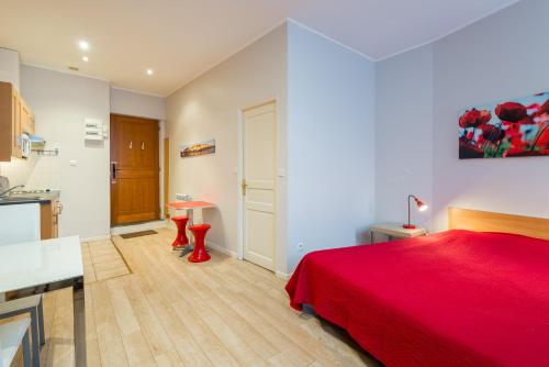 1 dormitorio con cama roja y cocina en Les Studios De La Place (Part-Dieu), en Lyon