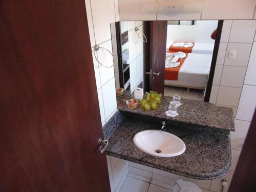 a bathroom with a sink and a mirror and a bed at Pousada Solar Ponta Negra in Natal