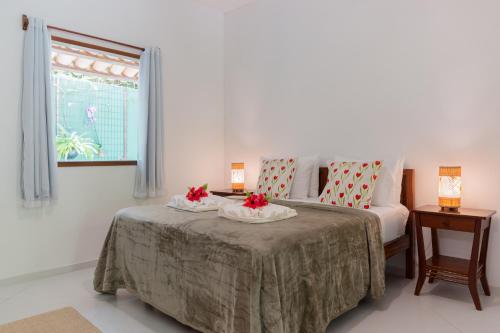 a bedroom with a bed with two tables and a window at Pousada Samambaia in Trancoso