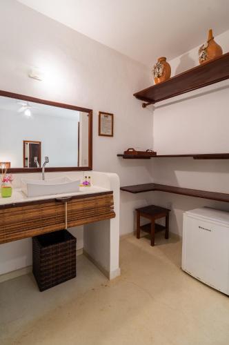 a bathroom with a sink and a large mirror at Pousada Samambaia in Trancoso
