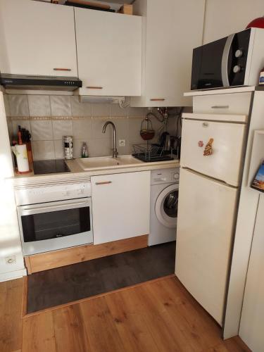 une cuisine avec des armoires blanches, un évier et un réfrigérateur dans l'établissement appartement 2pièces, au Cap d'Agde
