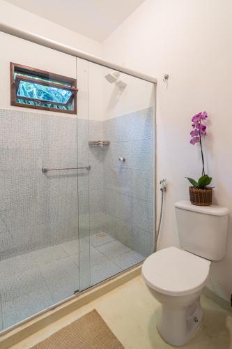 a bathroom with a toilet and a glass shower at Pousada Samambaia in Trancoso