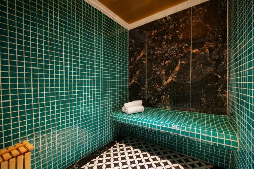 a green tiled bathroom with a green bench with a towel at Phat Diem Plaza Hotel in Ninh Binh