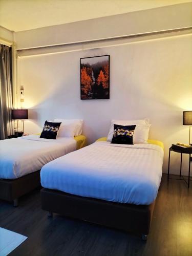 two beds in a hotel room with two lamps at ONEWAY Guest House BKK in Bangkok