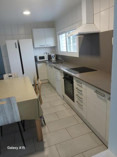 a kitchen with white cabinets and a table and a refrigerator at Appartement Almadrava Roses in Roses