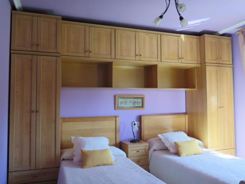 1 dormitorio con 2 camas y armarios de madera en K´María, en Pedrosa