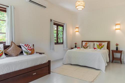 two beds in a room with white walls and windows at Pousada Samambaia in Trancoso