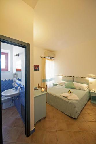 a bedroom with a bed and a bathroom with a sink at BUE MARINO Hotel & Roof Lounge in Cala Gonone
