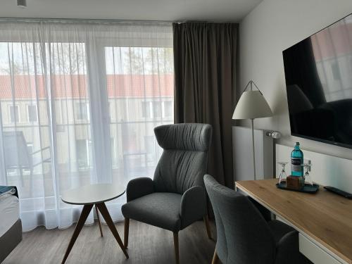 a room with a chair and a table and a television at Hotel Schöne Aussicht in Wilhelmshaven